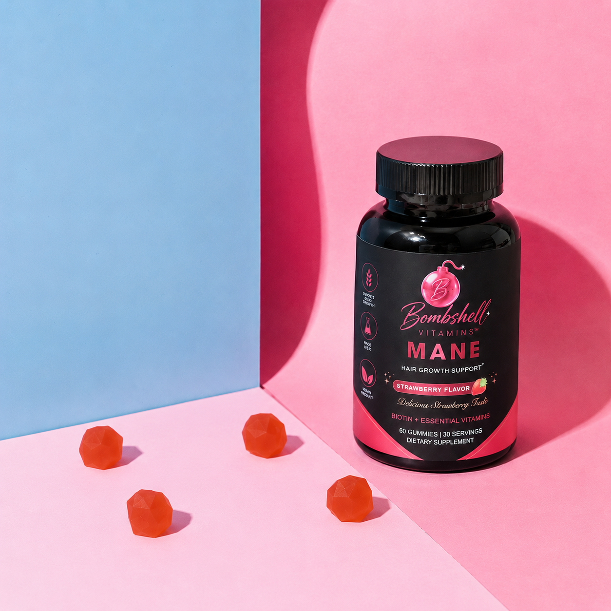 A bottle of Bombshell Mane beside four gummies on a pink and blue background